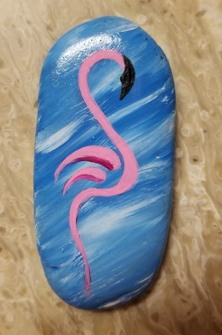 a painted rock with a pink flamingo on it