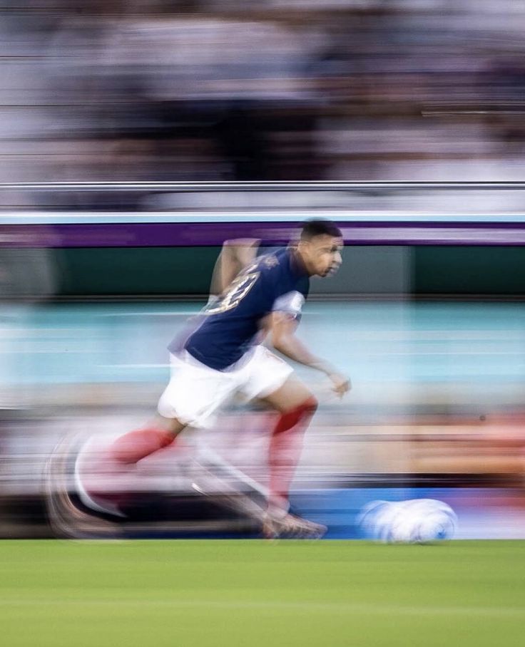 a blurry photo of a soccer player running with the ball in front of him