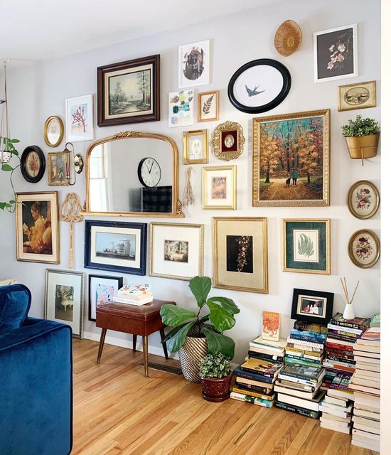 a living room filled with lots of framed pictures on the wall above a blue couch