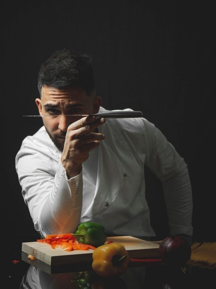 a man holding a knife in front of a cutting board