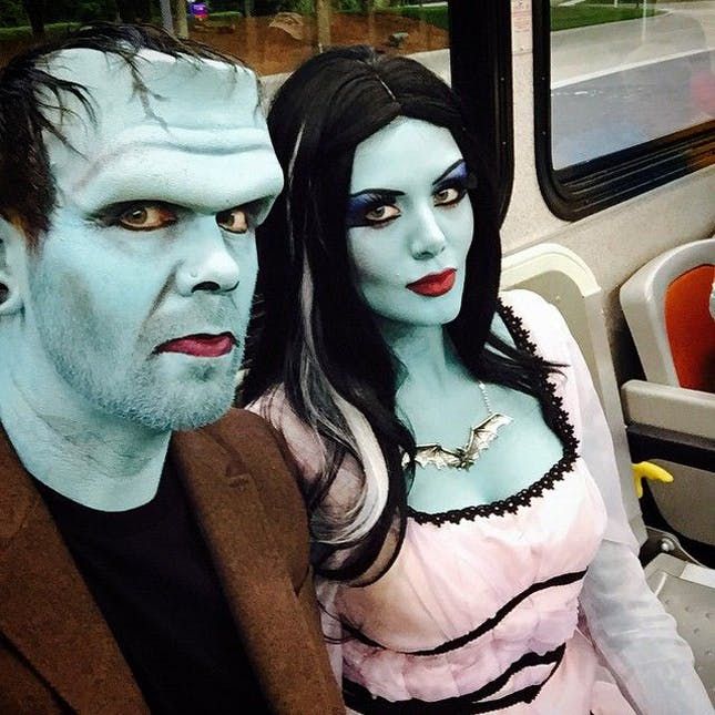 two people dressed up in costumes on a bus with one person wearing makeup and the other as a zombie