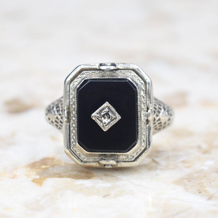 Antique 14k white gold Art Deco era flip ring. One side has a carved shell cameo. The other, an onyx stone set with a small diamond. The filigree setting has blossom details on the shoulders and along the band.  Era: Art Deco c.1920 Markings: 14k PATENTED  Materials: 14k white gold, shell, onyx, diamond  Ring Size: 6.5 (Comes with one free resizing by our jeweler) Weight: 3.1 grams Face measures 14mm x 12mm Condition: Excellent antique condition with minor wear from age  Shipping is free in the United States  Follow us on Instagram @LUXXORVintage Formal White Gold Ring With Black Enamel, Formal White Gold Enamel Ring With Black Detail, Elegant Black Enamel Wedding Ring, Classic White Gold Rings With Black Enamel, Classic Formal Enamel Ring, Vintage Diamond Enamel Ring, Silver Art Deco Signet Ring With Polished Finish, Art Deco Silver Signet Ring With Polished Finish, Antique Signet Ring With Diamond Accents For Formal