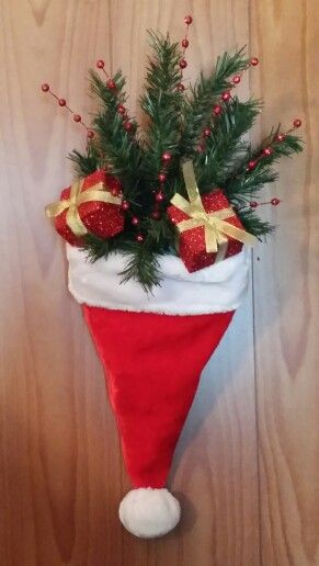 a red and white christmas stocking hanging on a wooden wall with pine cones, berries and holly