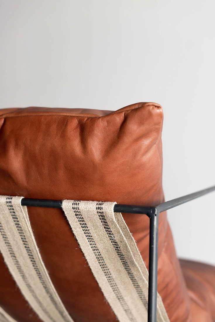 a brown leather chair sitting next to a white wall