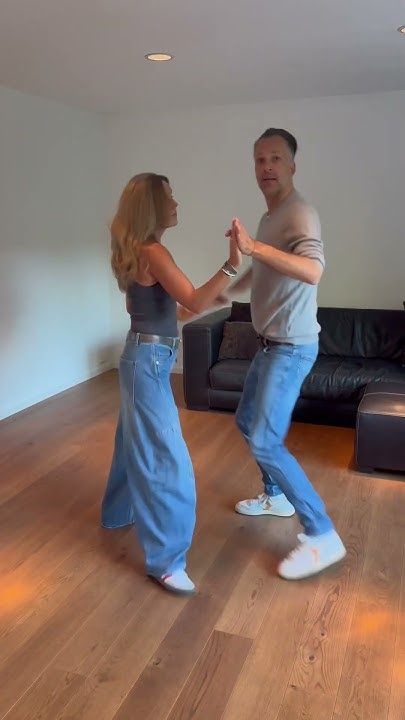 a man and woman are dancing in the living room