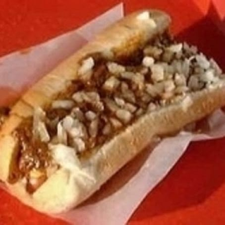 a hot dog with toppings sitting on top of a red table