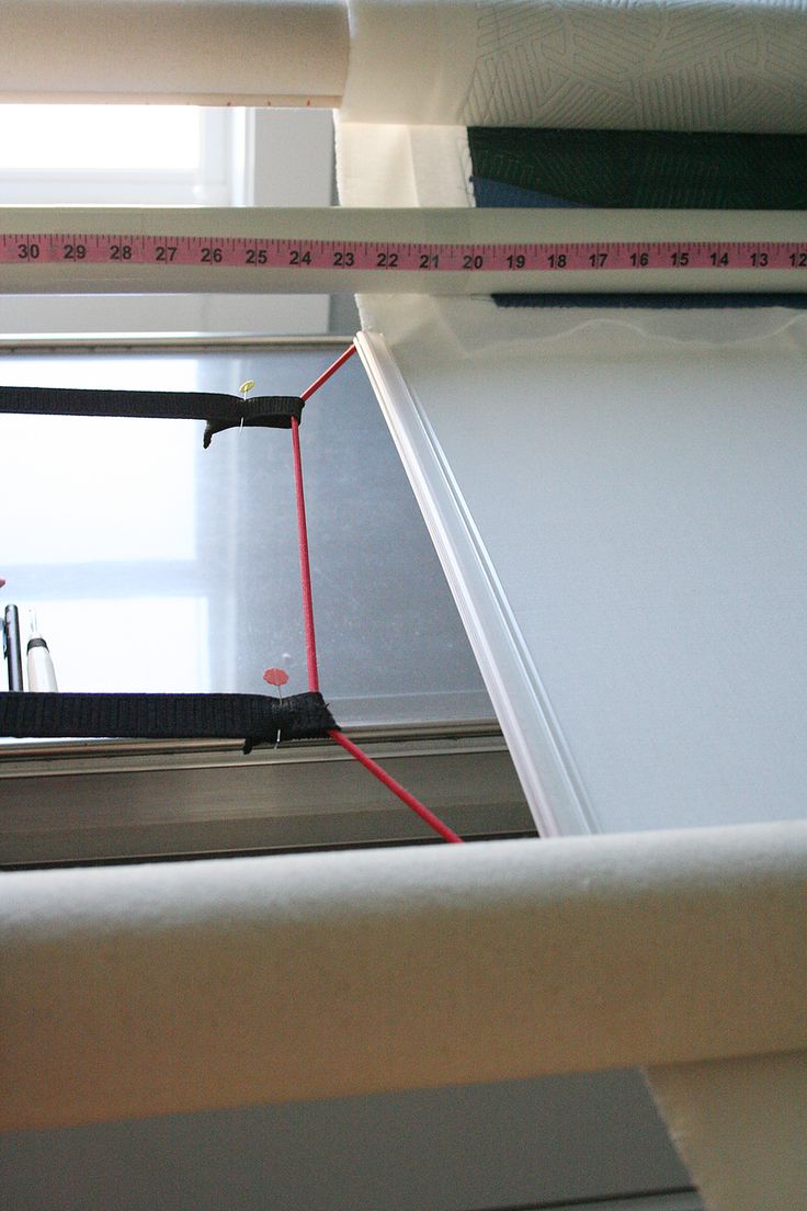 an open window with measuring tape on the outside and red string attached to it's side