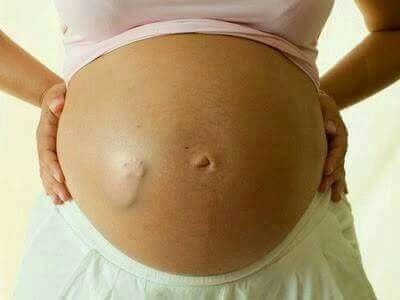 a pregnant woman with her hands on her belly, showing the size of her stomach