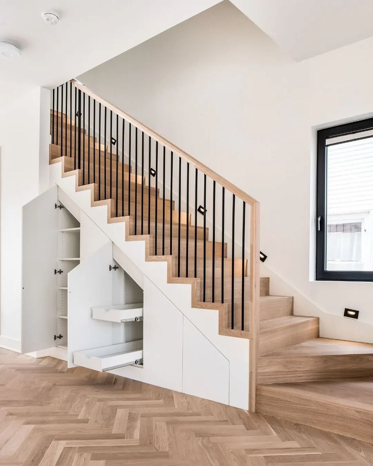 an empty room with wooden floors and white walls, stairs leading up to the second floor