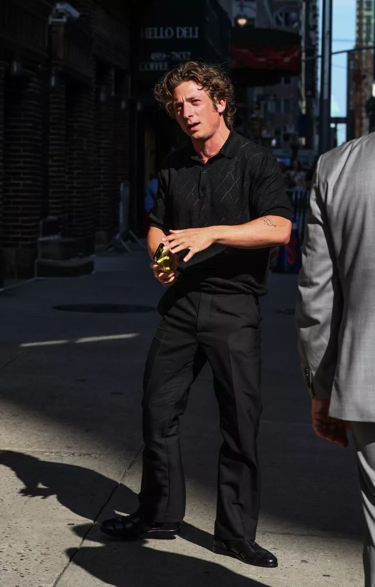 a man standing on the sidewalk holding an apple