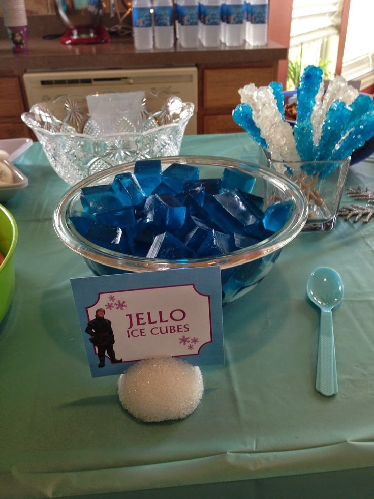 there is a bowl of ice cubes on the table with spoons next to it