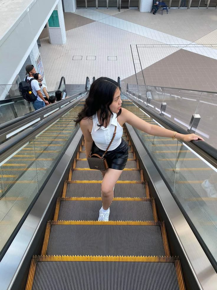 a woman riding an escalator with her hand on the railing and looking up