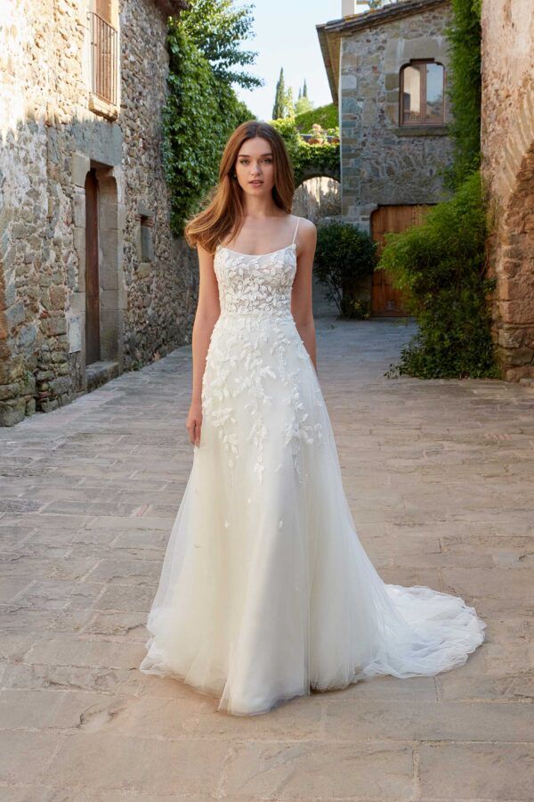 a woman in a white wedding dress standing on a stone walkway with an old building behind her