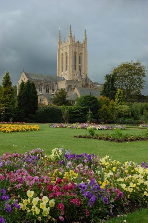 a garden with flowers in the foreground and a large building in the back ground