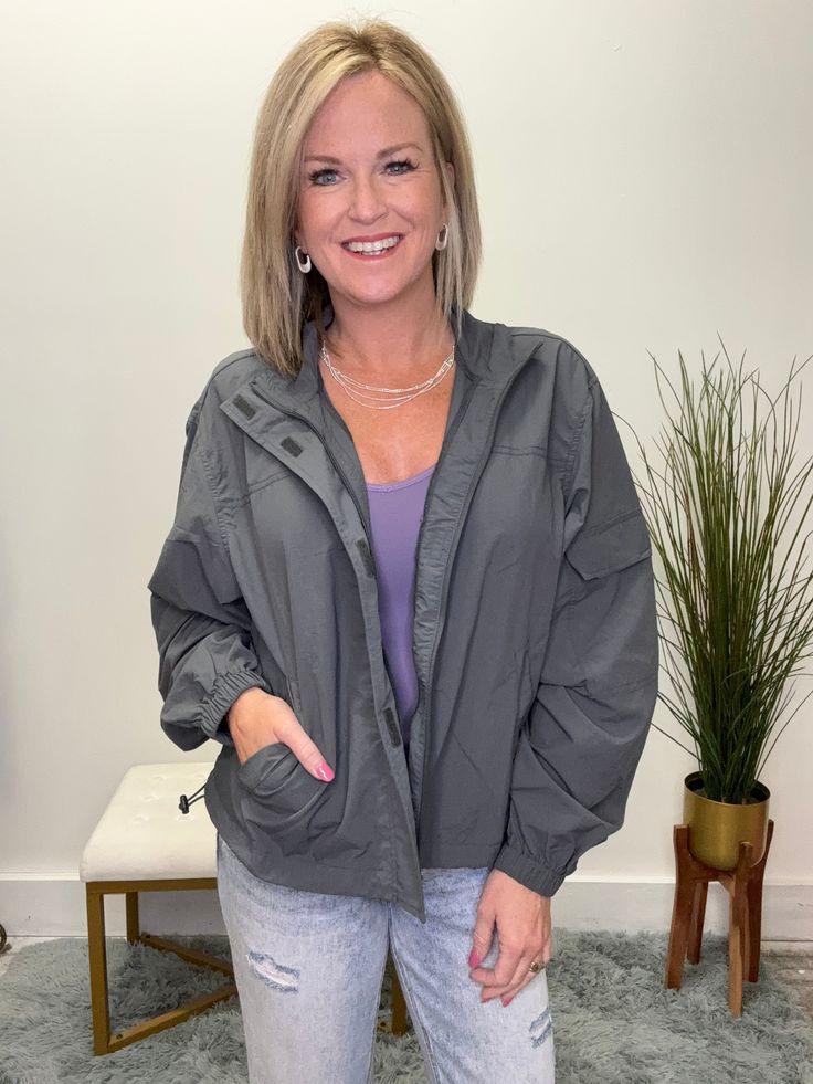 Get ready for cool weather in style with The Perfect Cool Weather Jacket in Gray! This lightweight jacket features a zipper front with Velcro closure, a convenient cargo-style pocket on the sleeve, and an elastic strap to adjust the hem. Stay warm and stylish all season long! Fit: This runs true to size. Stacy is 5’3 wearing a size small. Trendy Outdoor Utility Jacket With Pockets, Trendy Utility Jacket With Pockets For Outdoor, Fall Windbreaker With Cargo Pockets For Workwear, Utility Windbreaker With Multiple Pockets For Spring, Spring Utility Windbreaker With Multiple Pockets, Trendy Outdoor Windbreaker With Pockets, Versatile Outerwear For Spring Outdoor Activities, Versatile Spring Outerwear For Outdoor Activities, Trendy Stretch Outerwear For Outdoor