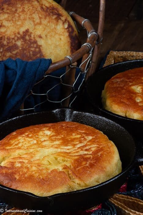 two pans filled with bread sitting on top of a blue cloth covered tablecloth