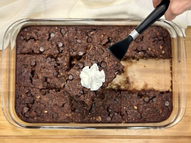 someone is spreading icing on some brownies in a baking dish with a spatula