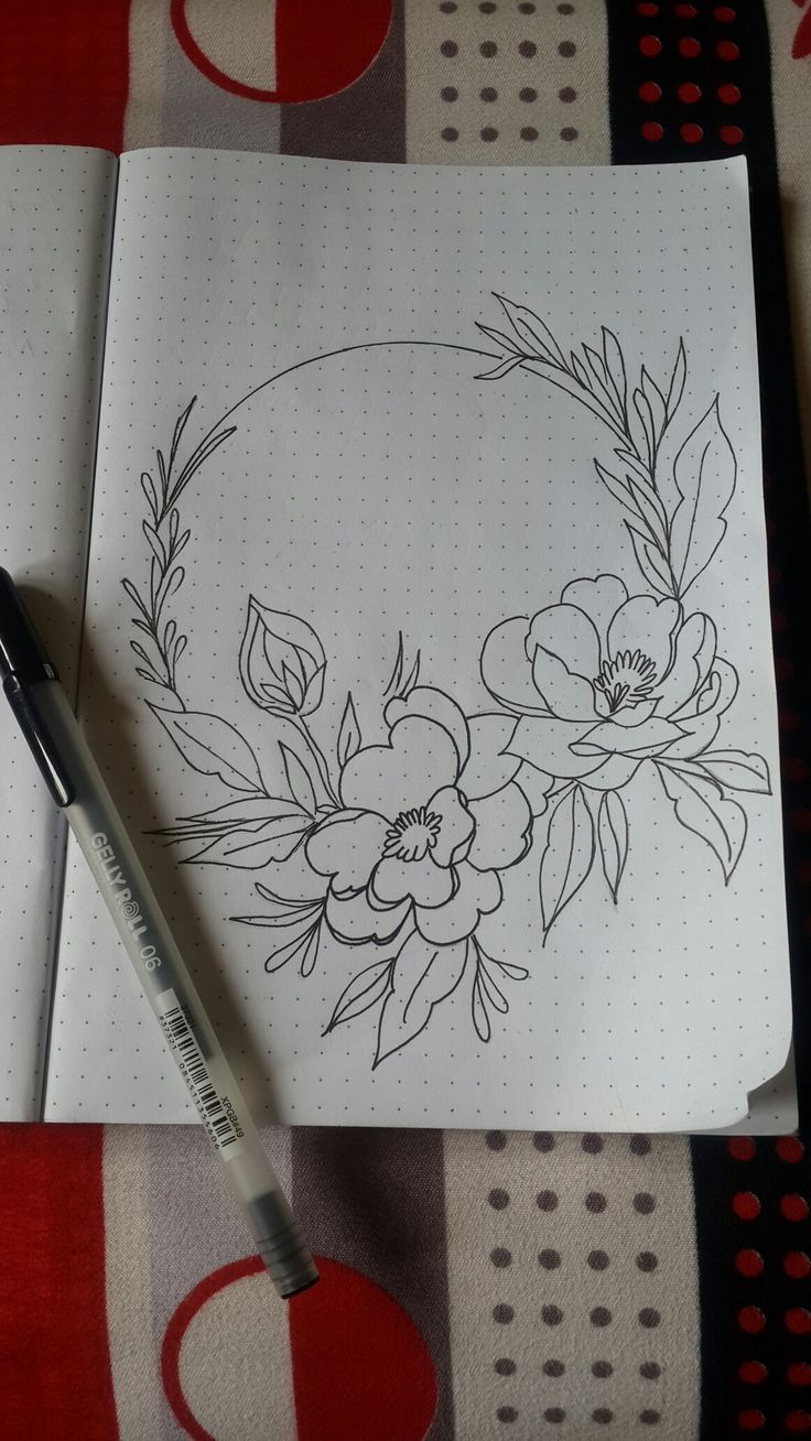 a pen is sitting on top of a notebook with flowers and leaves drawn on it