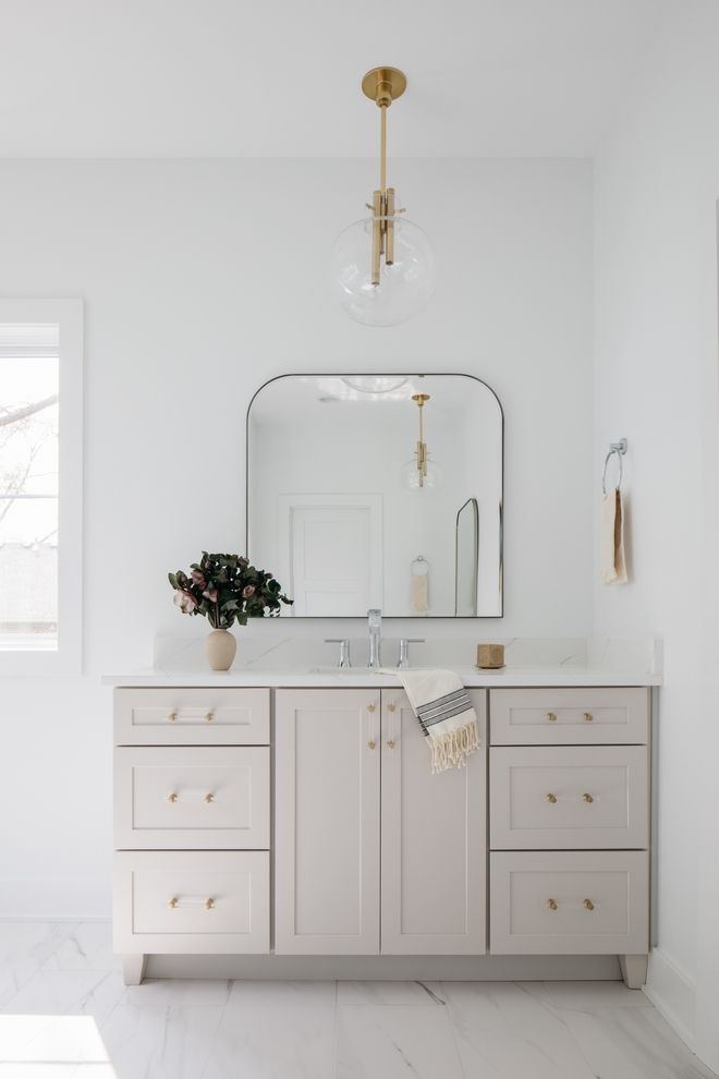 a bathroom with white cabinets and a large mirror above the sink, along with a potted plant