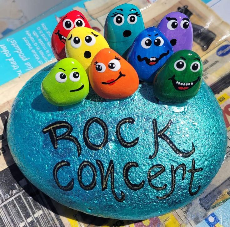 some rocks with faces painted on them and the words rock concert written in black ink