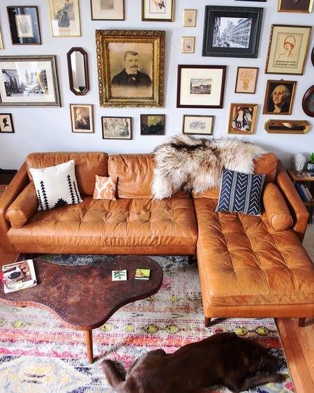 a living room filled with furniture and lots of framed pictures on the wall above it