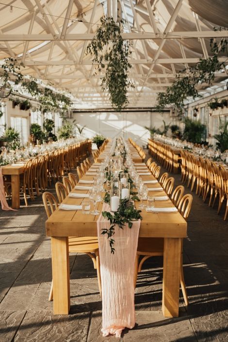 a long table is set up with candles and greenery for an outdoor wedding reception