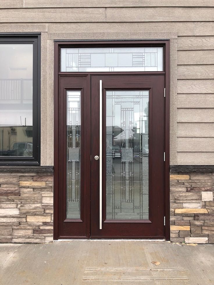 the front entrance to a building with two glass doors and brick wall on either side