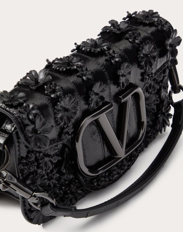 Valentino Garavani Locò small shoulder bag in eel skin with flower appliqué and metallic VLogo Signature detail. Equipped with both a detachable sliding chain and a detachable handle, this accessory can be worn as a crossbody/shoulder bag or carried as a handbag. - Tone-on-tone hardware - Magnetic closure - Removable leather handle - Shoulder strap with removable sliding chain - Suede leather lining. Interior: one slip pocket Shoulder strap drop length: min. 33 cm to max. 55 cm / min. 13.0 in. t Luxury Embroidered Top Handle Shoulder Bag, Luxury Embroidered Clutch Shoulder Bag, Formal Embellished Leather Shoulder Bag, Designer Embellished Leather Shoulder Bag, Luxury Embroidered Crossbody Bag, Luxury Leather Embellished Bag, Luxury Embellished Leather Bag, Luxury Leather Embellished Shoulder Bag, Luxury Embellished Leather Shoulder Bag