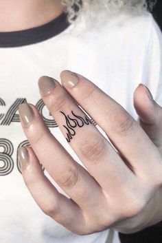 a woman's hand with a small tattoo on her left thumb and the word love written in black ink