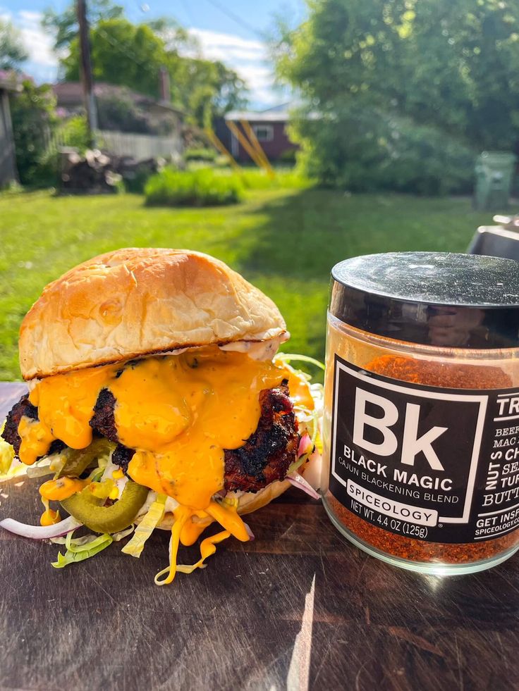 a burger with cheese and lettuce next to a jar of bbq sauce