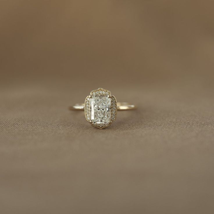 an engagement ring with a cushion cut diamond in the center on a brown background,