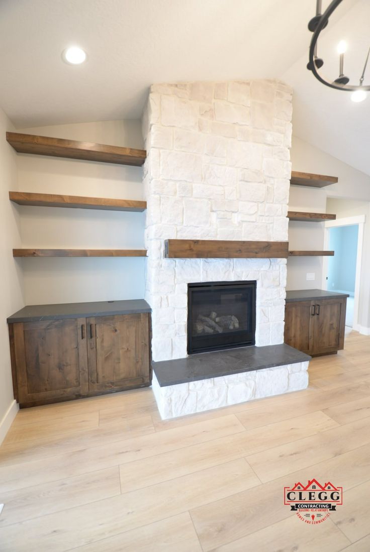 an empty living room with a fireplace and built in shelves