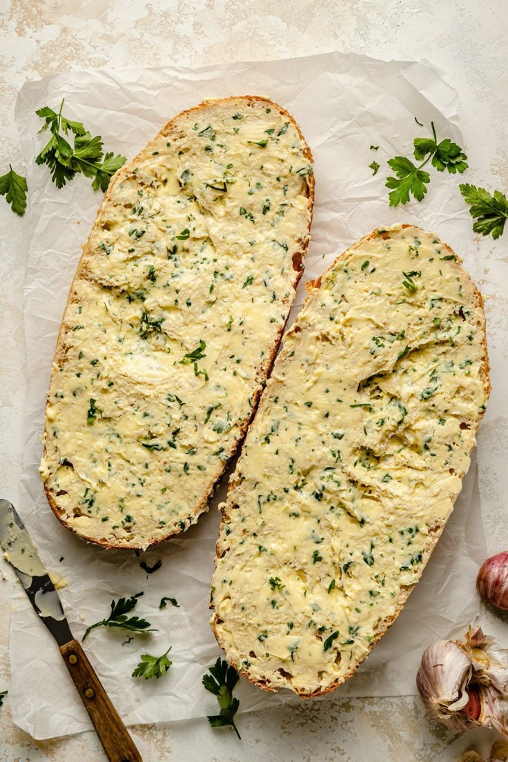 two pieces of bread with cheese and herbs on top next to garlic, parsley