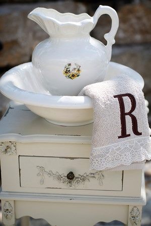 a white table topped with a plate and a vase filled with flowers next to a monogrammed dish towel