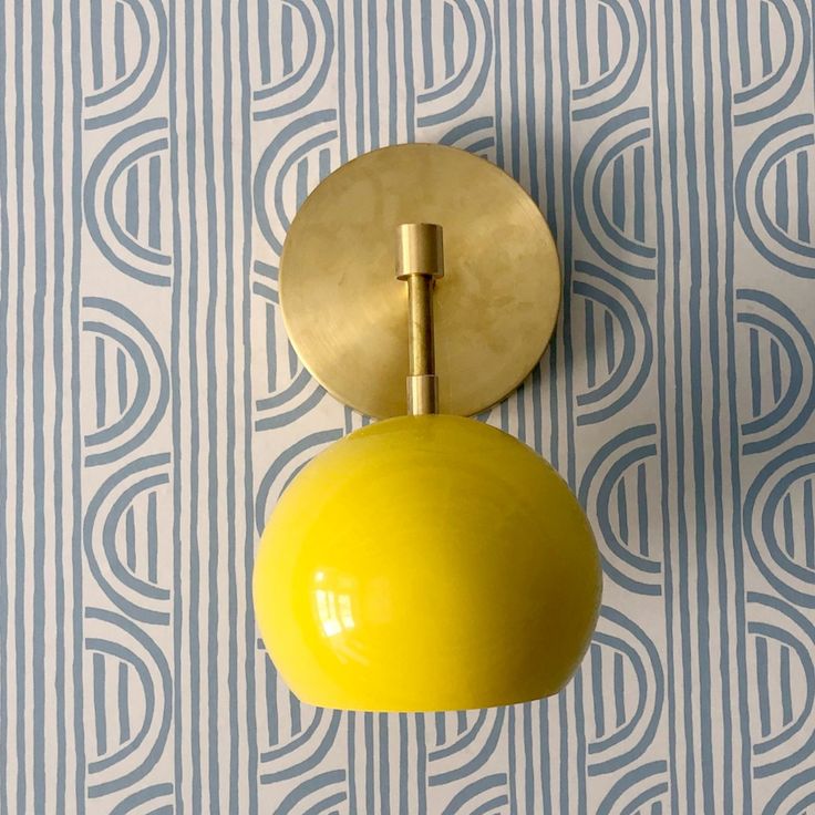 a yellow light is hanging on the wall next to a blue and white striped wallpaper