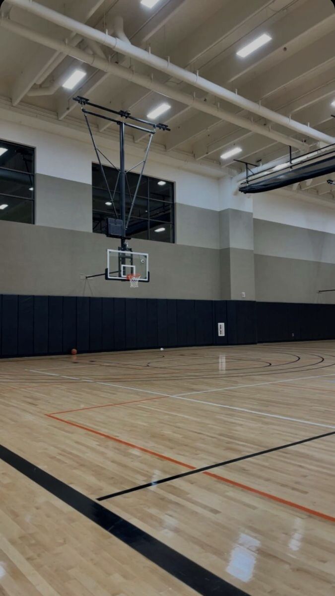 an indoor basketball court with hard wood flooring and lights on the side wall is empty