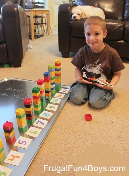 a young boy sitting on the floor next to a game board with blocks and numbers