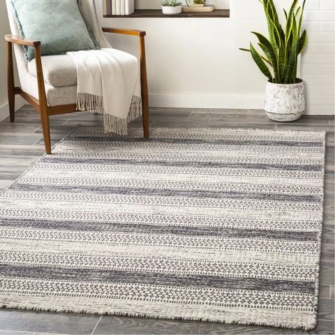 a living room area with a chair, potted plant and rug on the floor