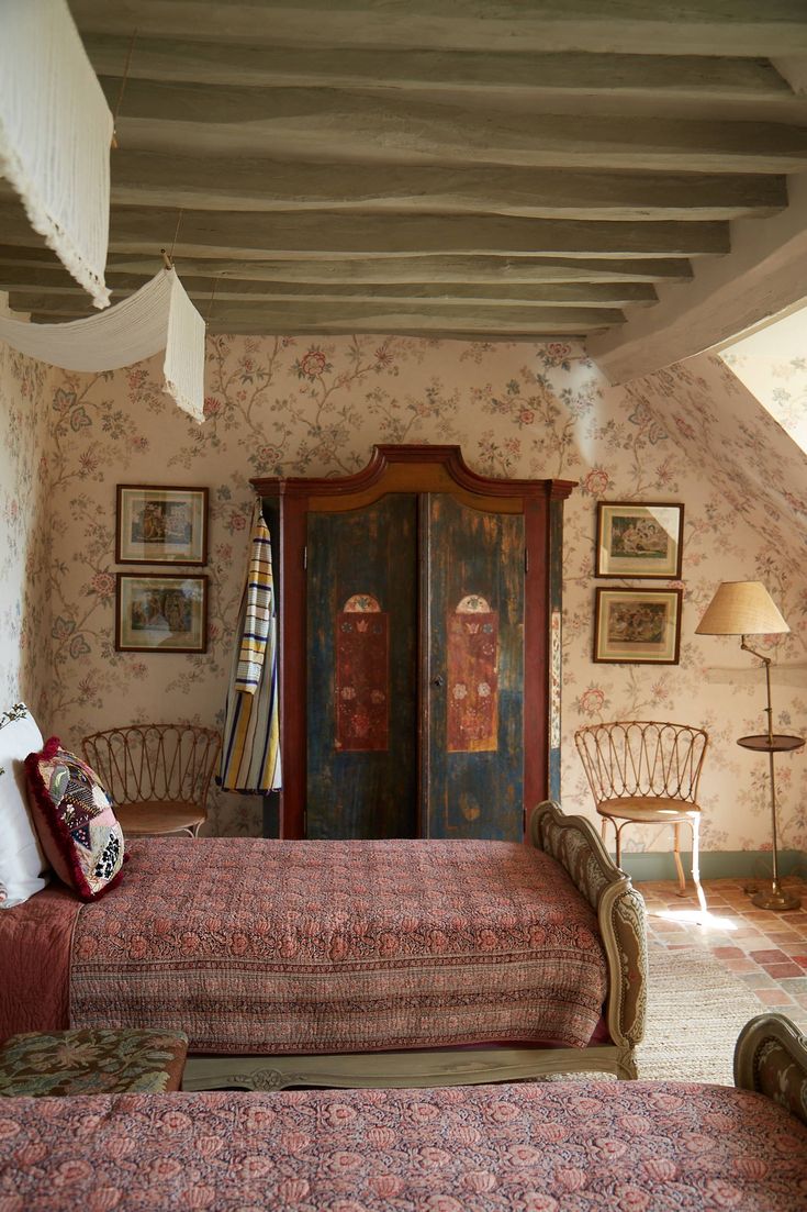 an old fashioned bedroom with floral wallpaper and antique furniture