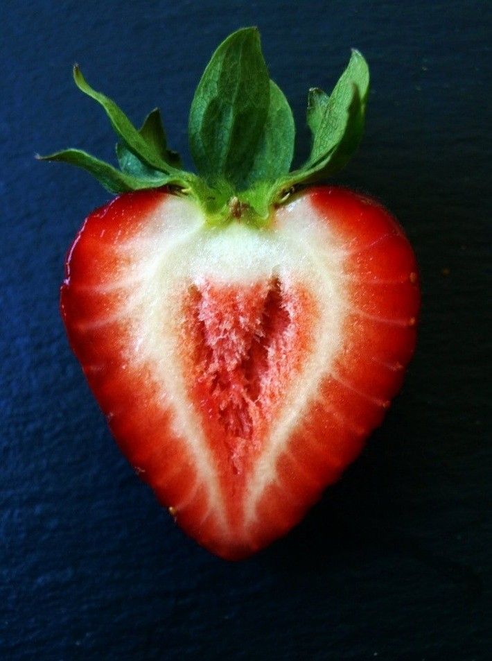 a half eaten strawberry with green leaves on top