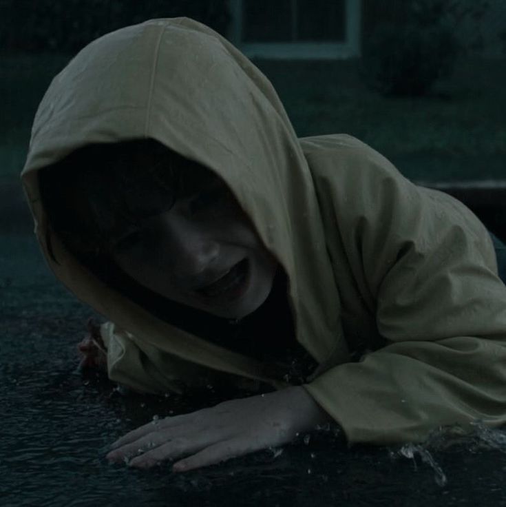 a woman in a hooded jacket is floating in the water with her hands on her head