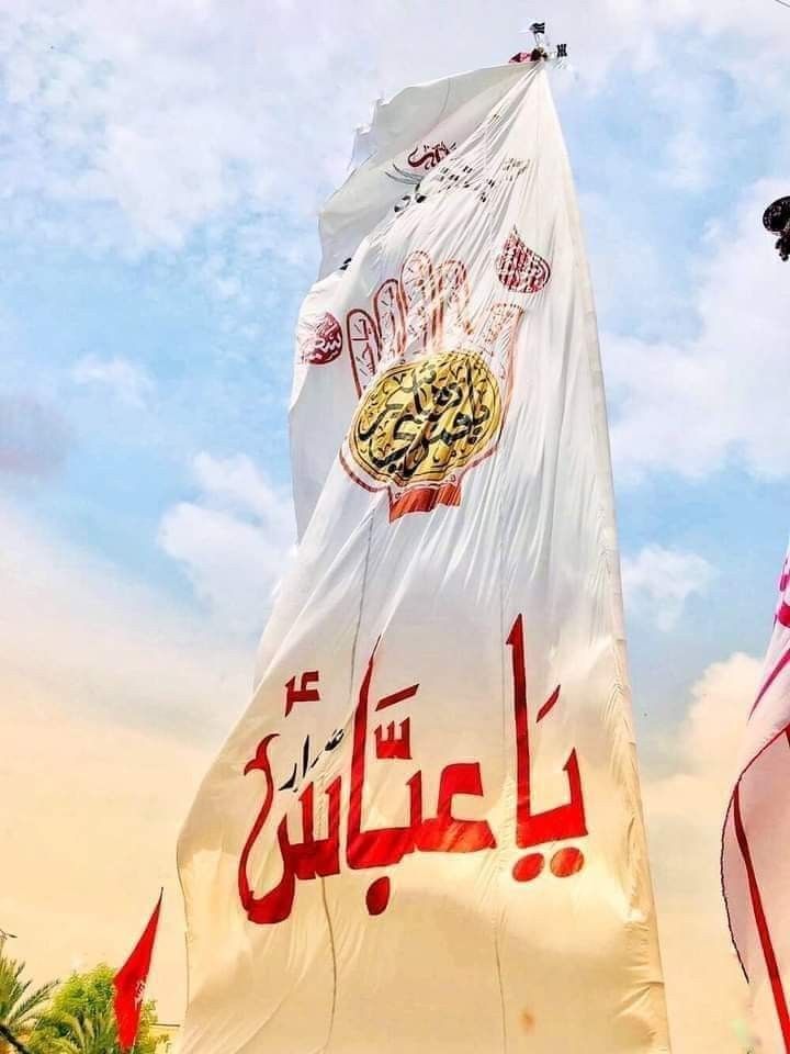 two large flags with arabic writing on them in front of a blue sky and white clouds