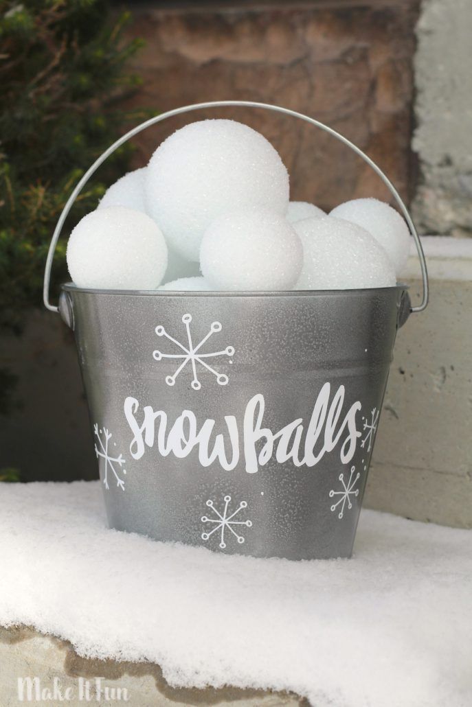 a bucket filled with snowballs sitting on top of a pile of snow