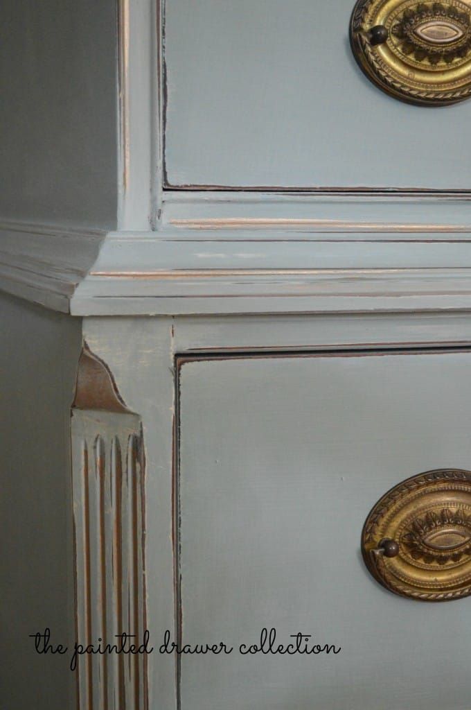 an old dresser with gold knobs on it's doors and drawer pulls, painted in pale blue