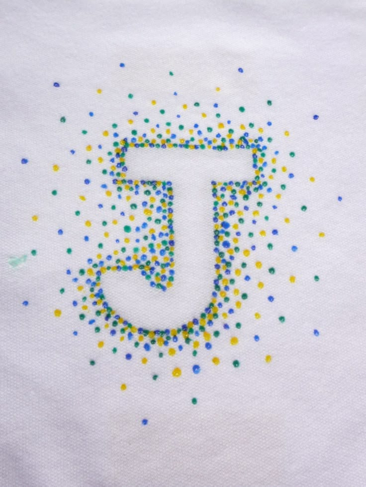 the letter t is made up of small colored dots on a white tee - shirt