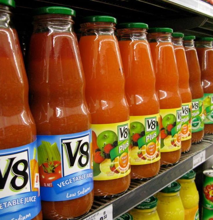 bottles of vegeable juice are on display in a grocery store's aisle