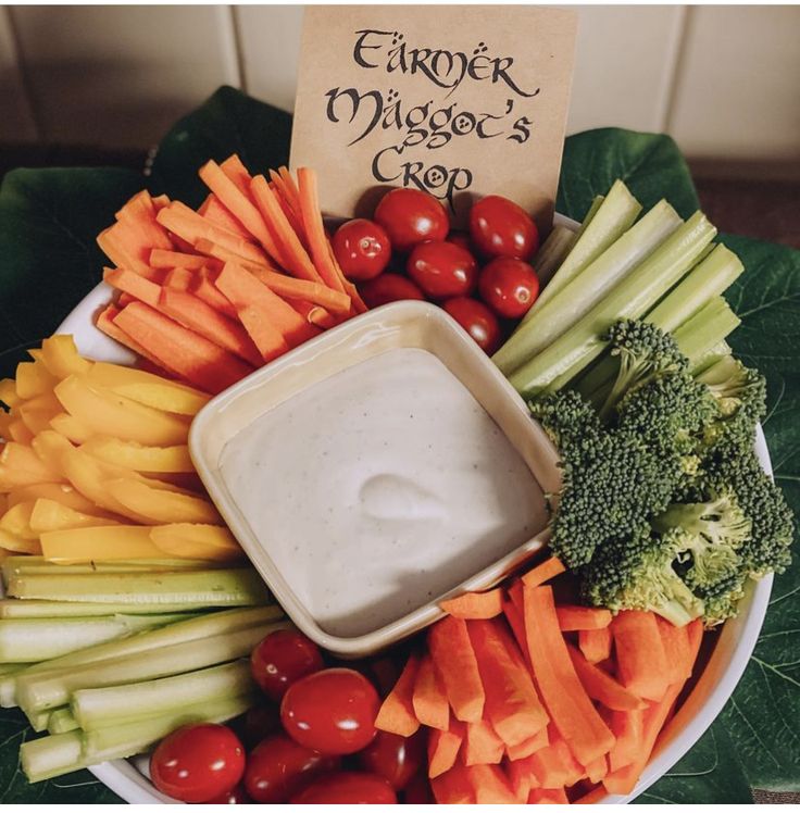 a platter filled with vegetables and dip surrounded by broccoli, tomatoes, carrots, celery