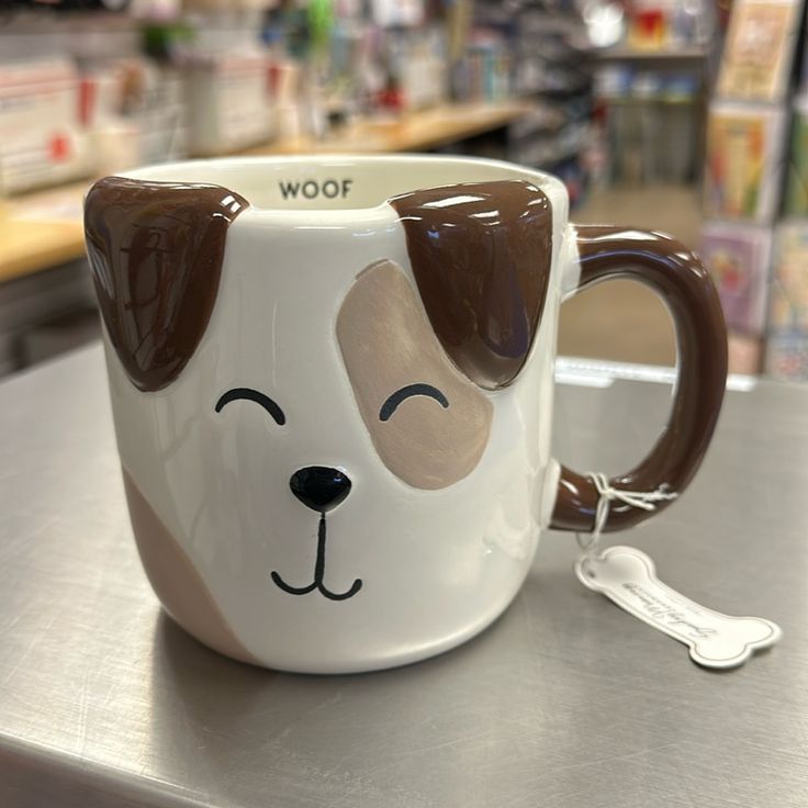 a white and brown dog mug sitting on top of a counter next to a spoon