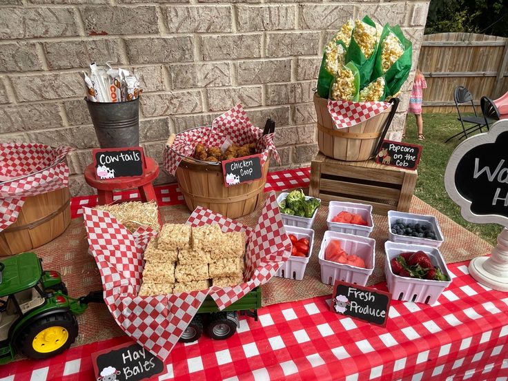 a table topped with lots of food next to a brick wall covered in red and white checkered paper