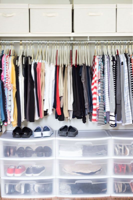 an organized closet with clear drawers and plastic bins filled with clothes, shoes and other items